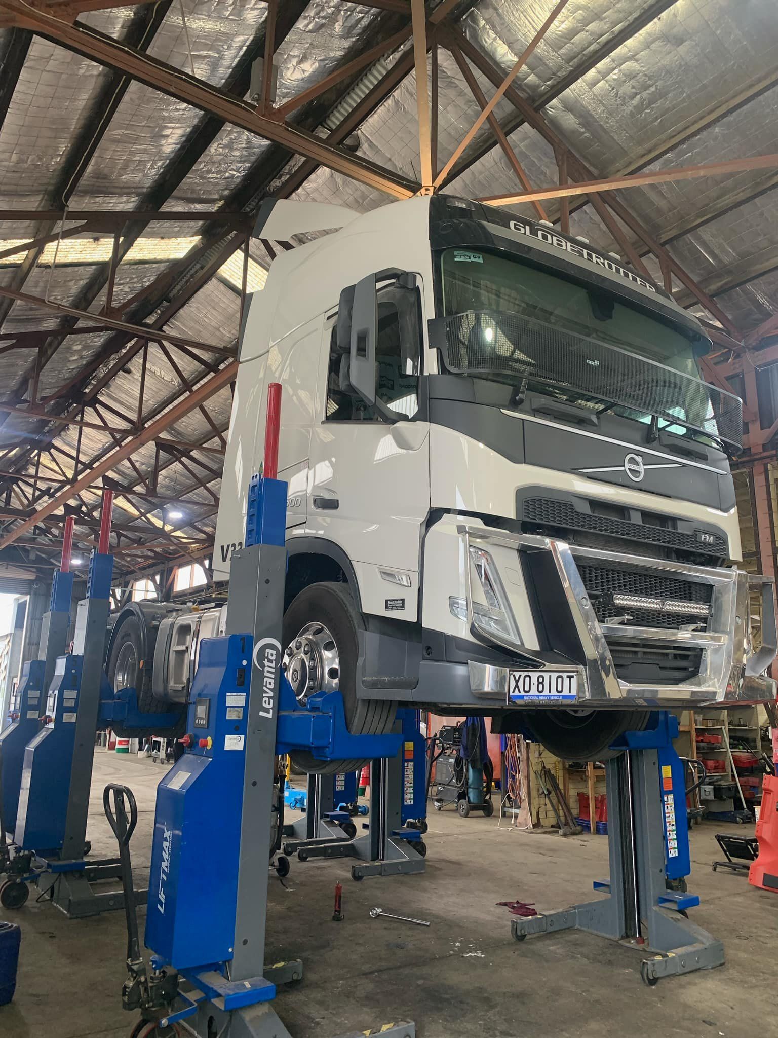White Volvo Truck On A Lift In A Repair Shop.  The Vehicle Is Raised Off The Ground, Likely For Maintenance Or Repairs — BDM Heavy Vehicle Repairs In Wauchope, NSW