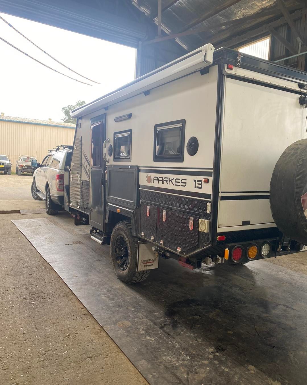 A camper trailer is parked in a garage next to a truck.— BDM Heavy Vehicle Repairs In Wauchope, NSW