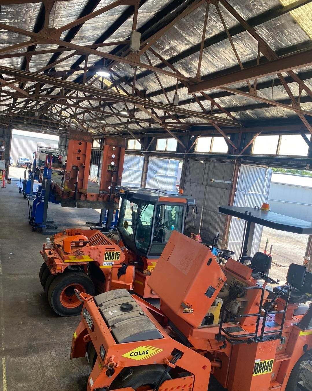 A row of orange tractors are parked in a garage.— BDM Heavy Vehicle Repairs In Wauchope, NSW