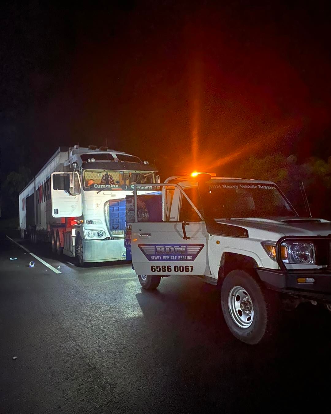 A Tow Truck is Towing a Train Down a Road at Night — BDM Heavy Vehicle Repairs In Wauchope, NSW
