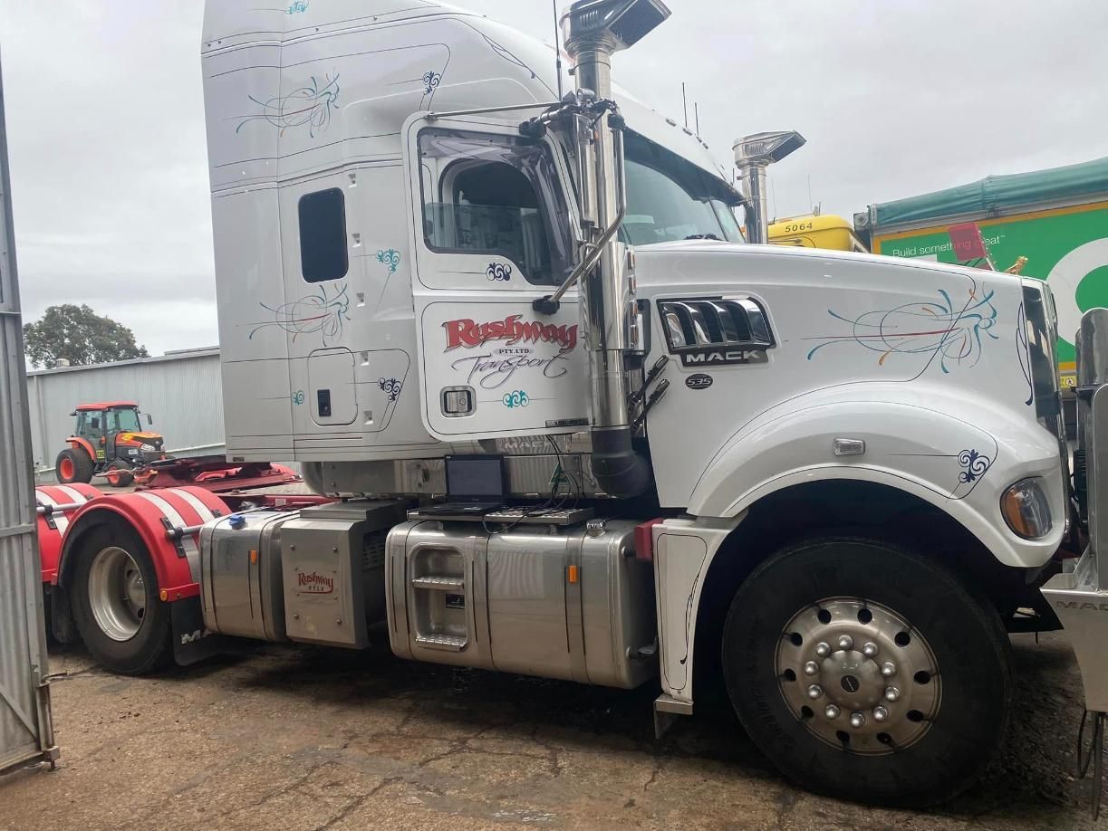 A white semi truck with a red trailer is parked in a parking lot. — BDM Heavy Vehicle Repairs In Wauchope, NSW