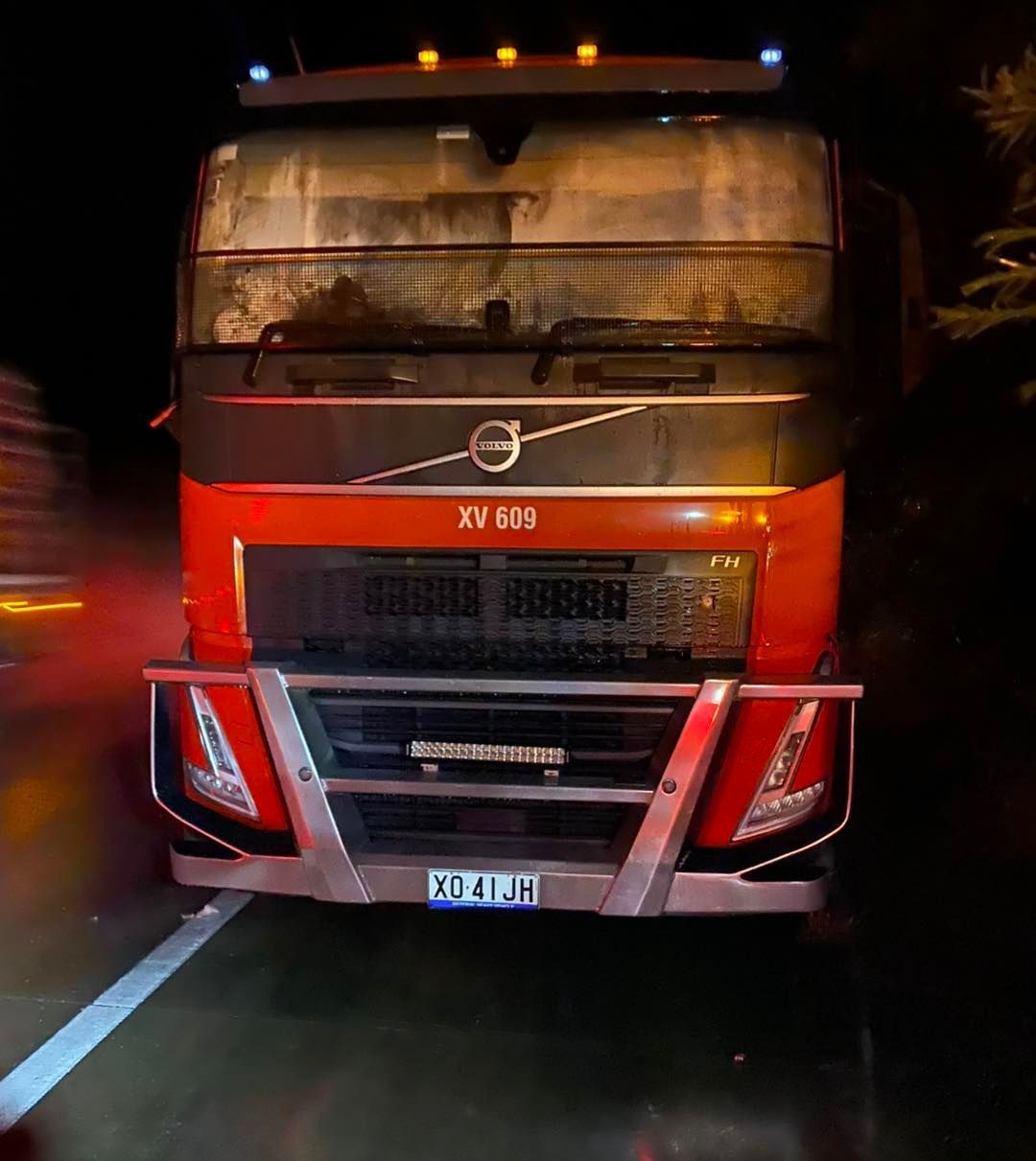 A red volvo truck is parked on the side of the road at night.— BDM Heavy Vehicle Repairs In Wauchope, NSW