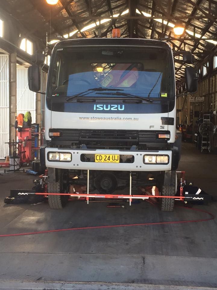 Isuzu Truck Undergoing Wheel Alignment Inside A Workshop, With Alignment Equipment In Use. Front View, Centered, Under Bright Lighting — BDM Heavy Vehicle Repairs In Wauchope, NSW