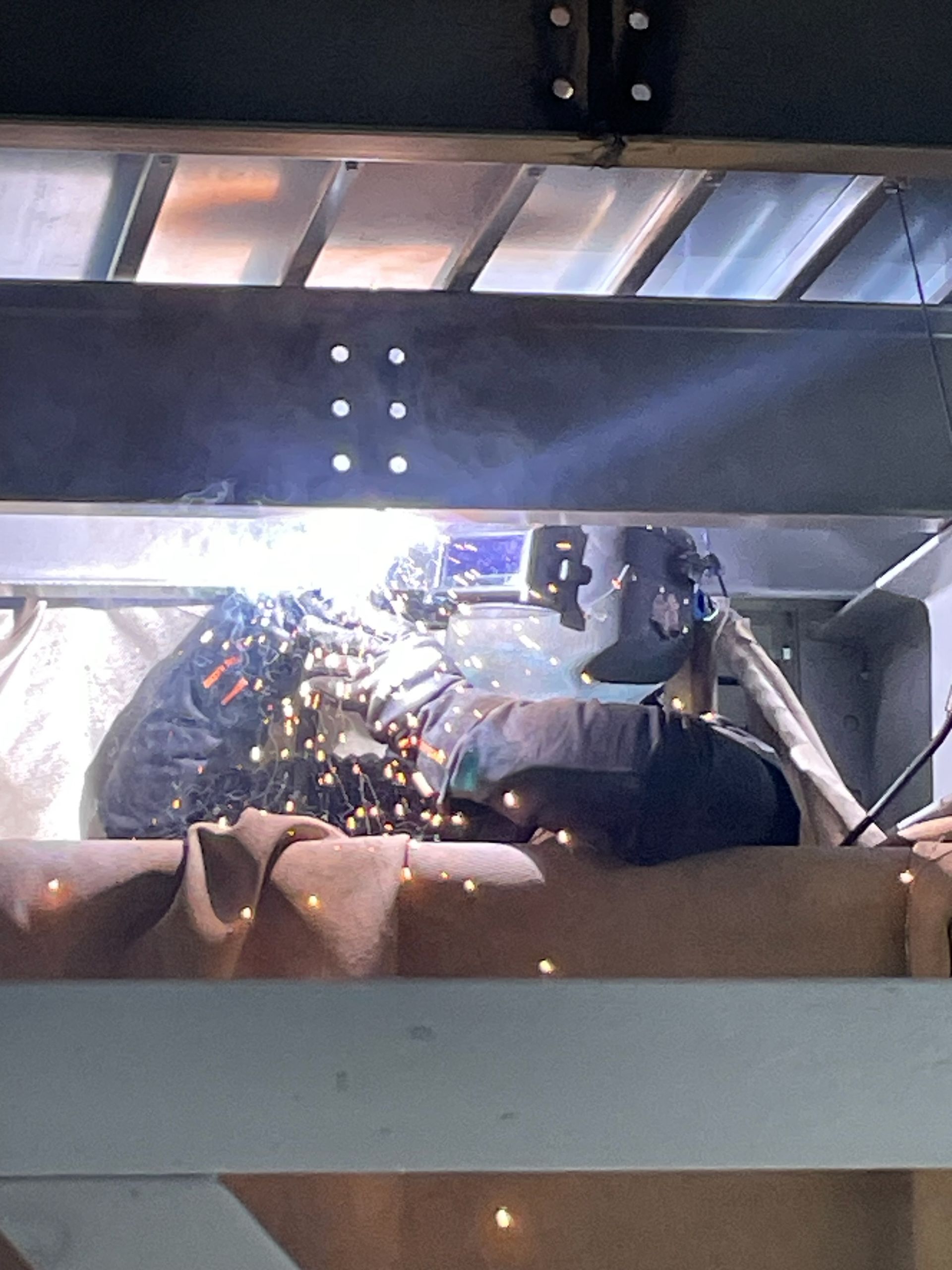 A man is welding a piece of metal in a factory.