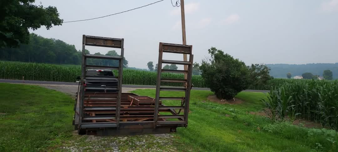 A trailer is parked in a grassy field next to a road.