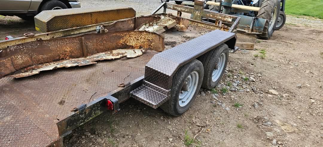 A trailer is parked in the dirt next to a tractor.