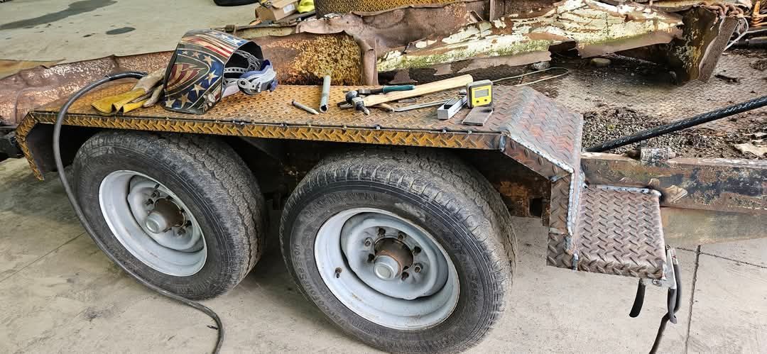 A rusty trailer with two wheels is sitting in a garage.