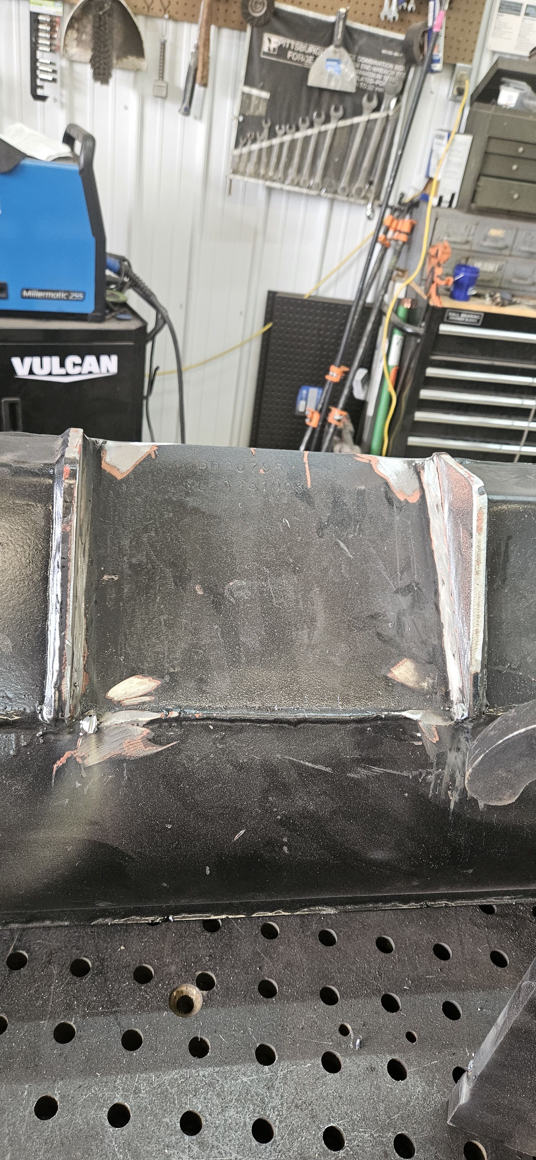 A piece of metal is sitting on top of a metal table in a garage.