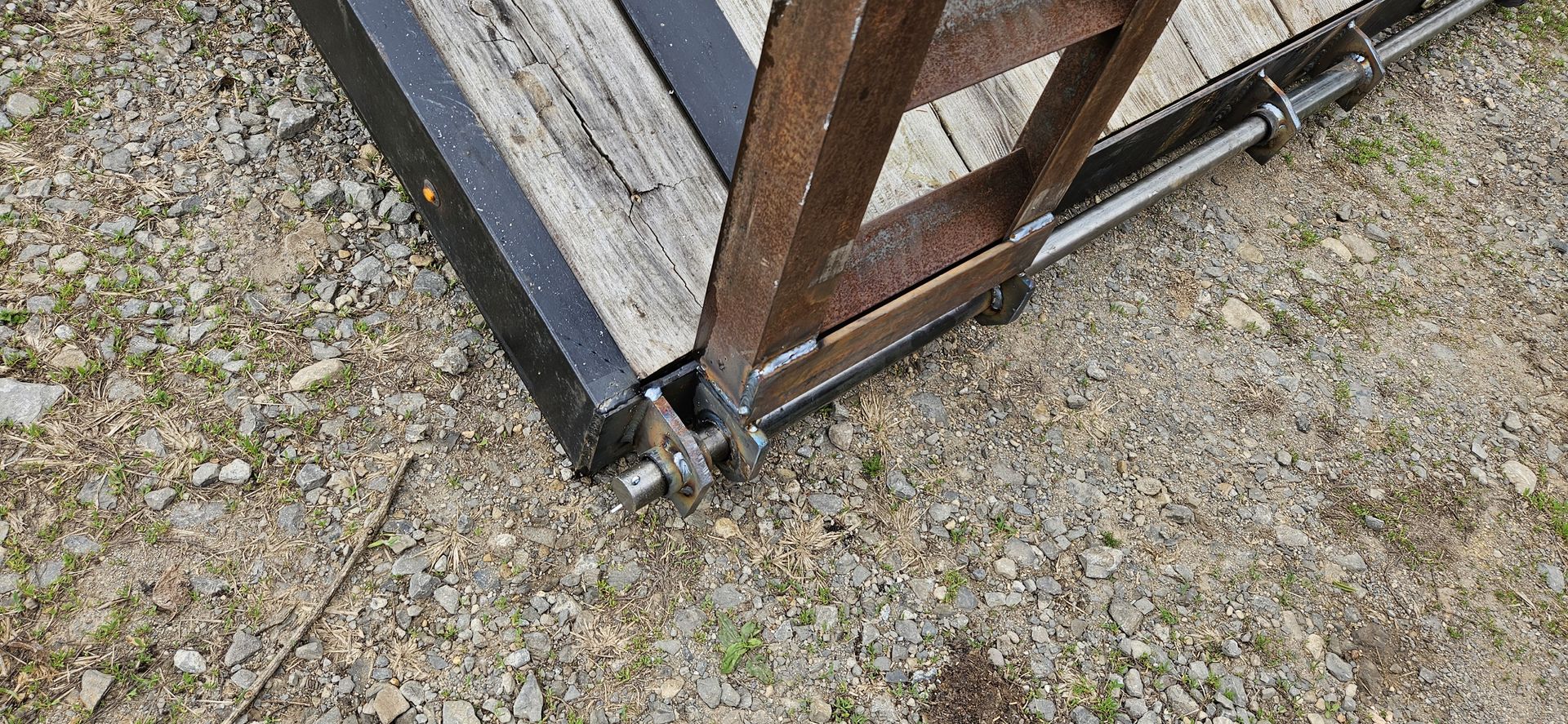A wooden ladder is sitting on top of a gravel road.