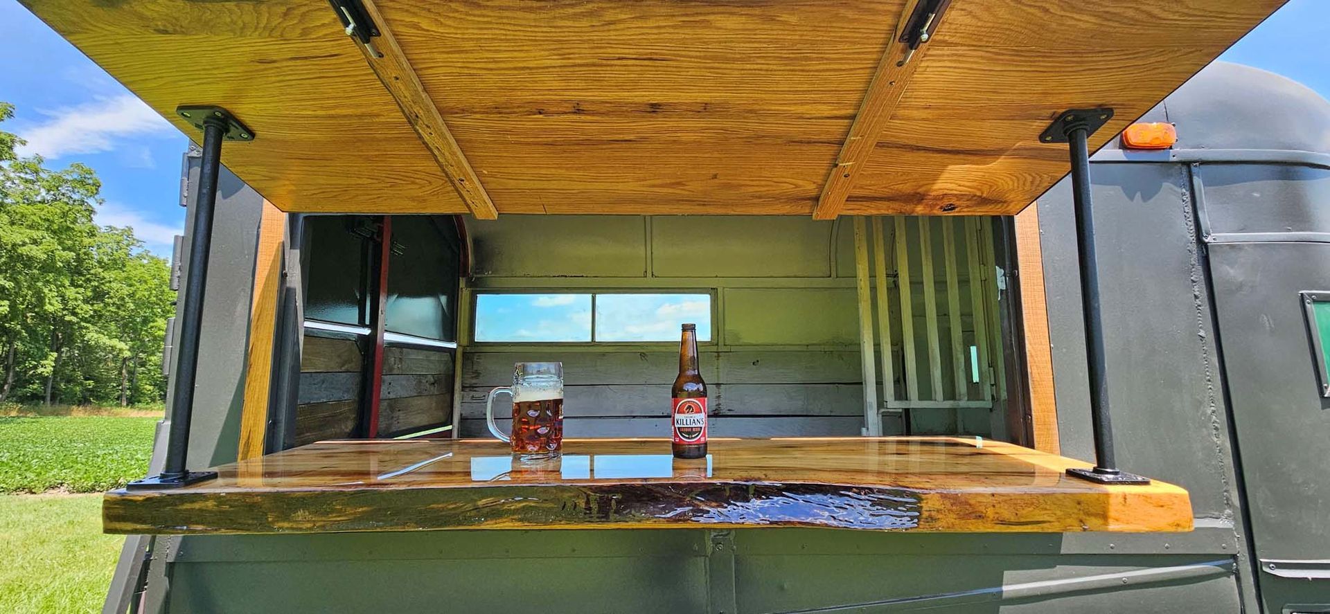 The inside of a food truck with a wooden counter and a bottle of soda on it.