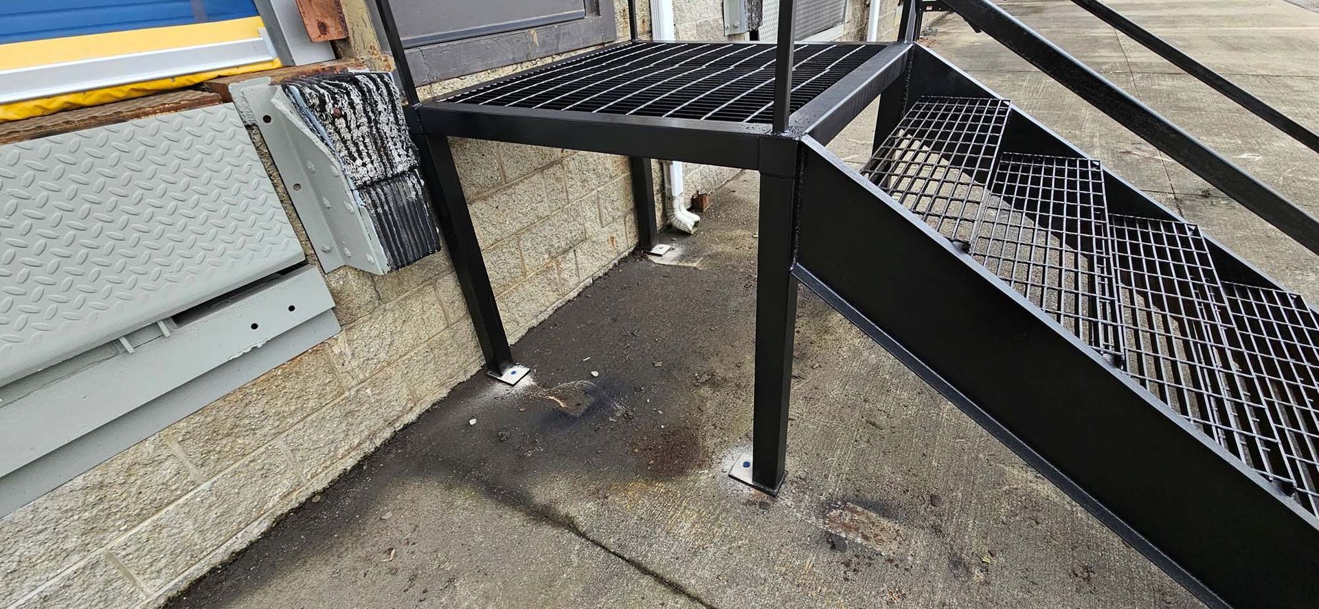 A black metal staircase is sitting on the sidewalk next to a building.