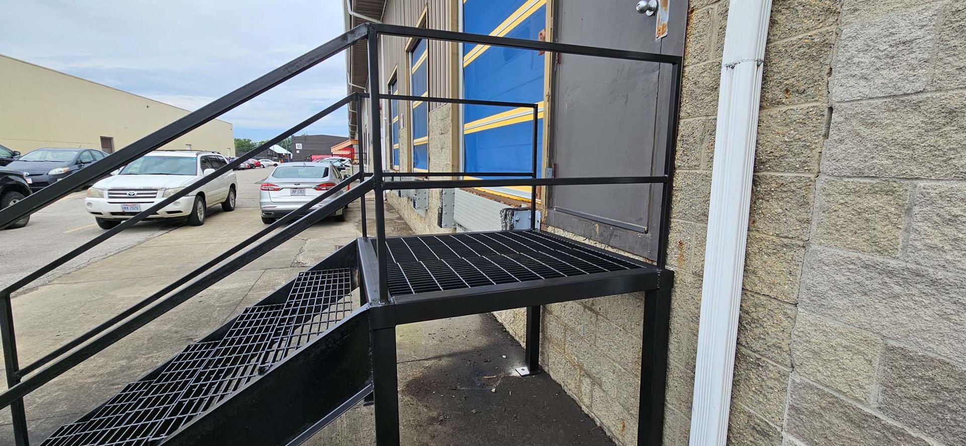 A set of stairs leading up to a building with cars parked in front of it.