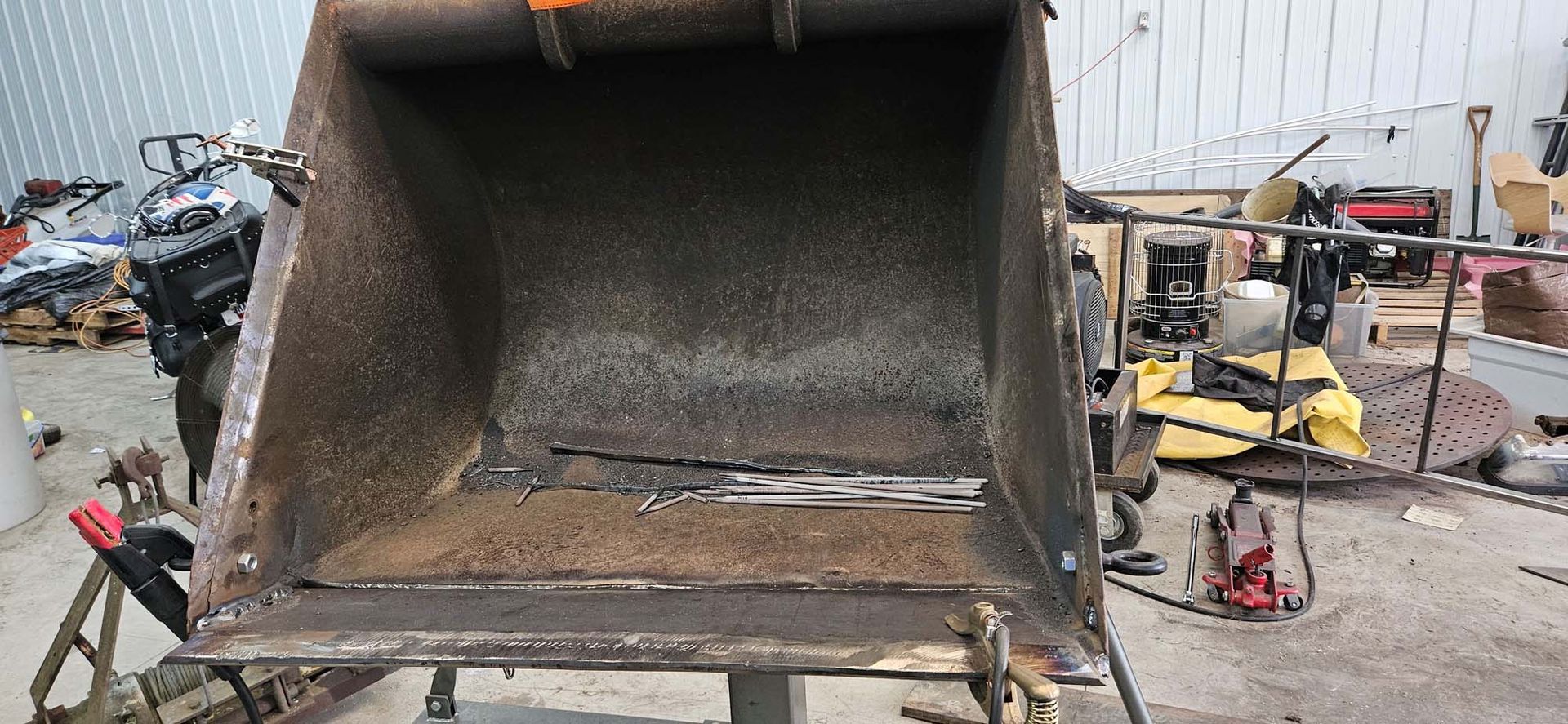 A large metal bucket is sitting on top of a table in a garage.