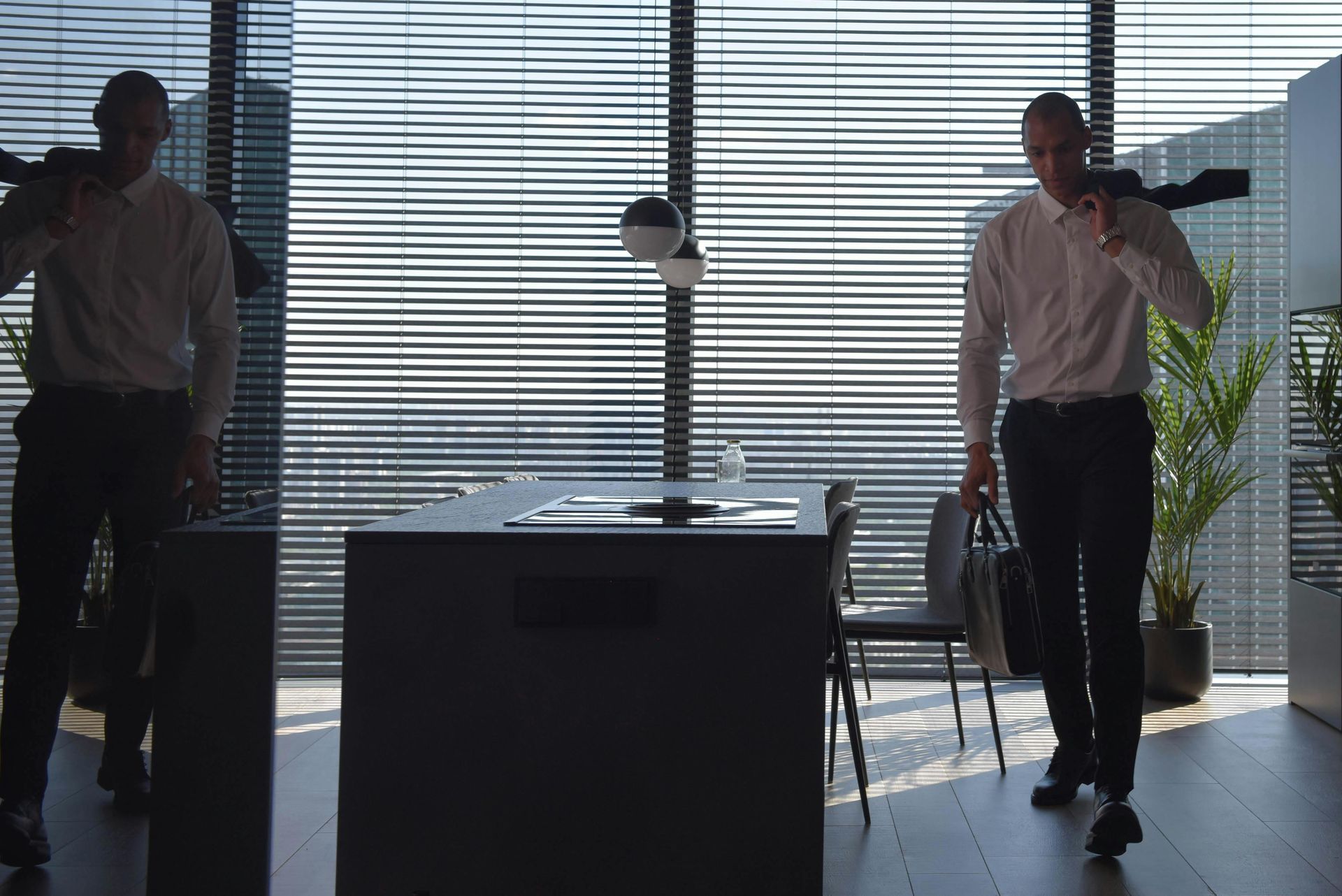 A man is sitting at a table with a laptop and shaking hands with a man.