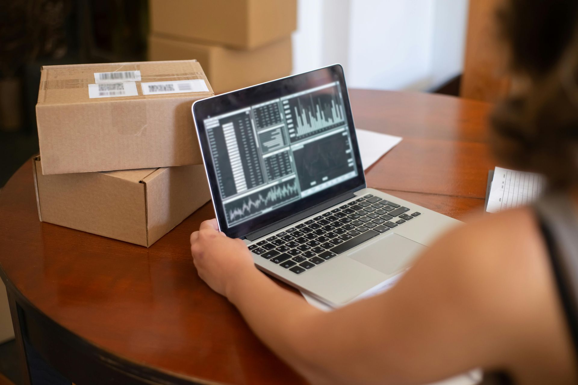 A man is sitting at a table with a laptop and shaking hands with a man.