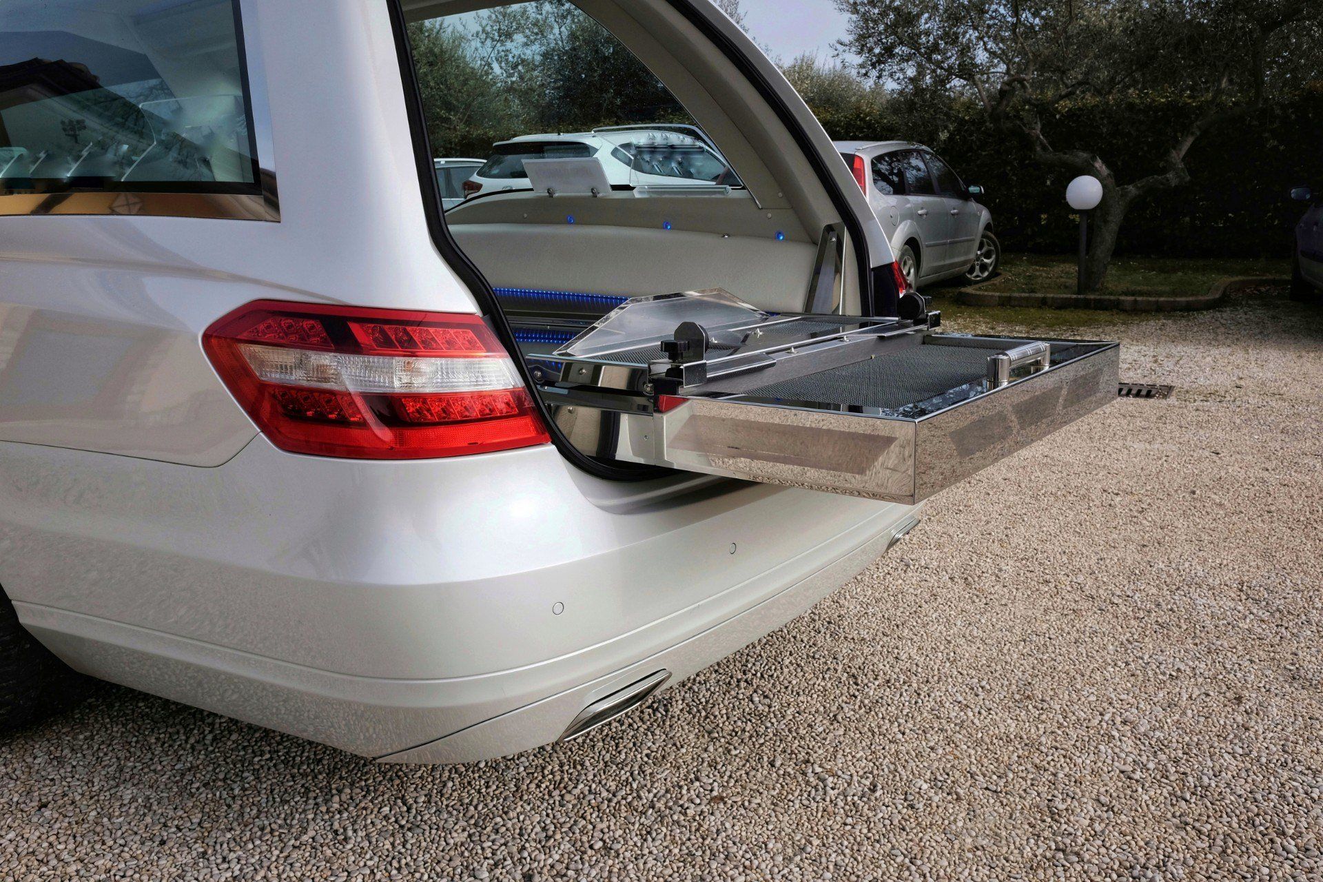 Station wagon bianca con il bagagliaio aperto, che rivela un vassoio che si estende verso l'esterno, all'aperto.