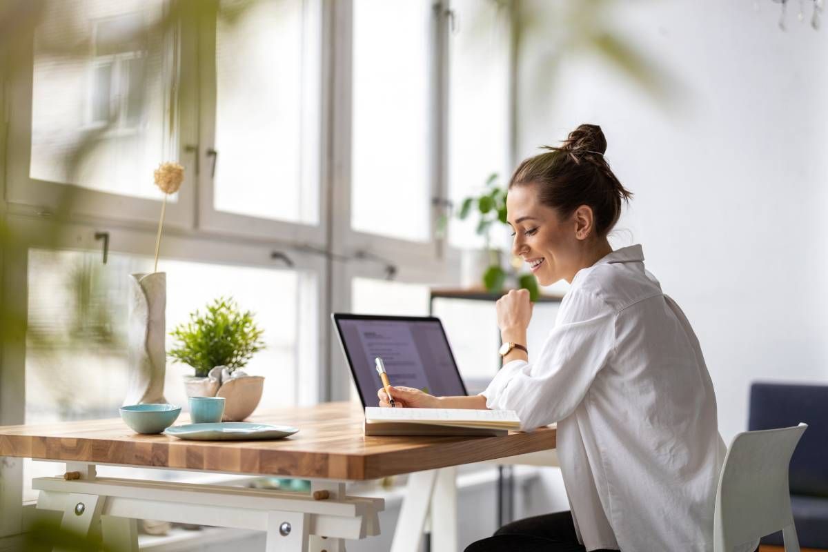 A woman working at her contemporary home office desk facing windows without Hunter Douglas window treatments at Window Magic Blinds & Drapery near Houston, TX