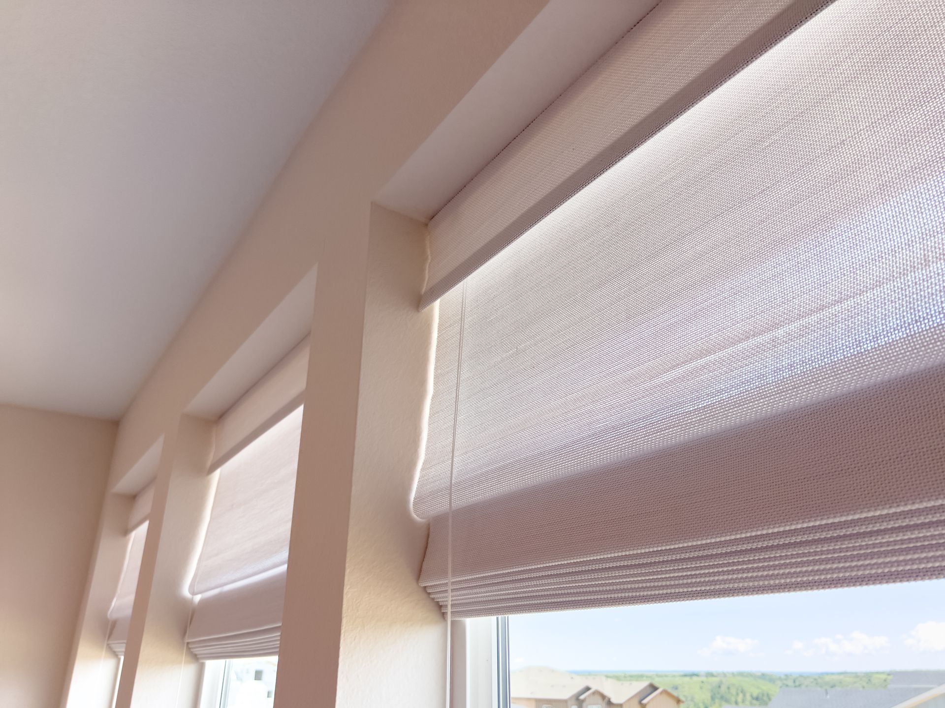 An up-close image of three windows in a home with custom Roman shades, pulled neatly up