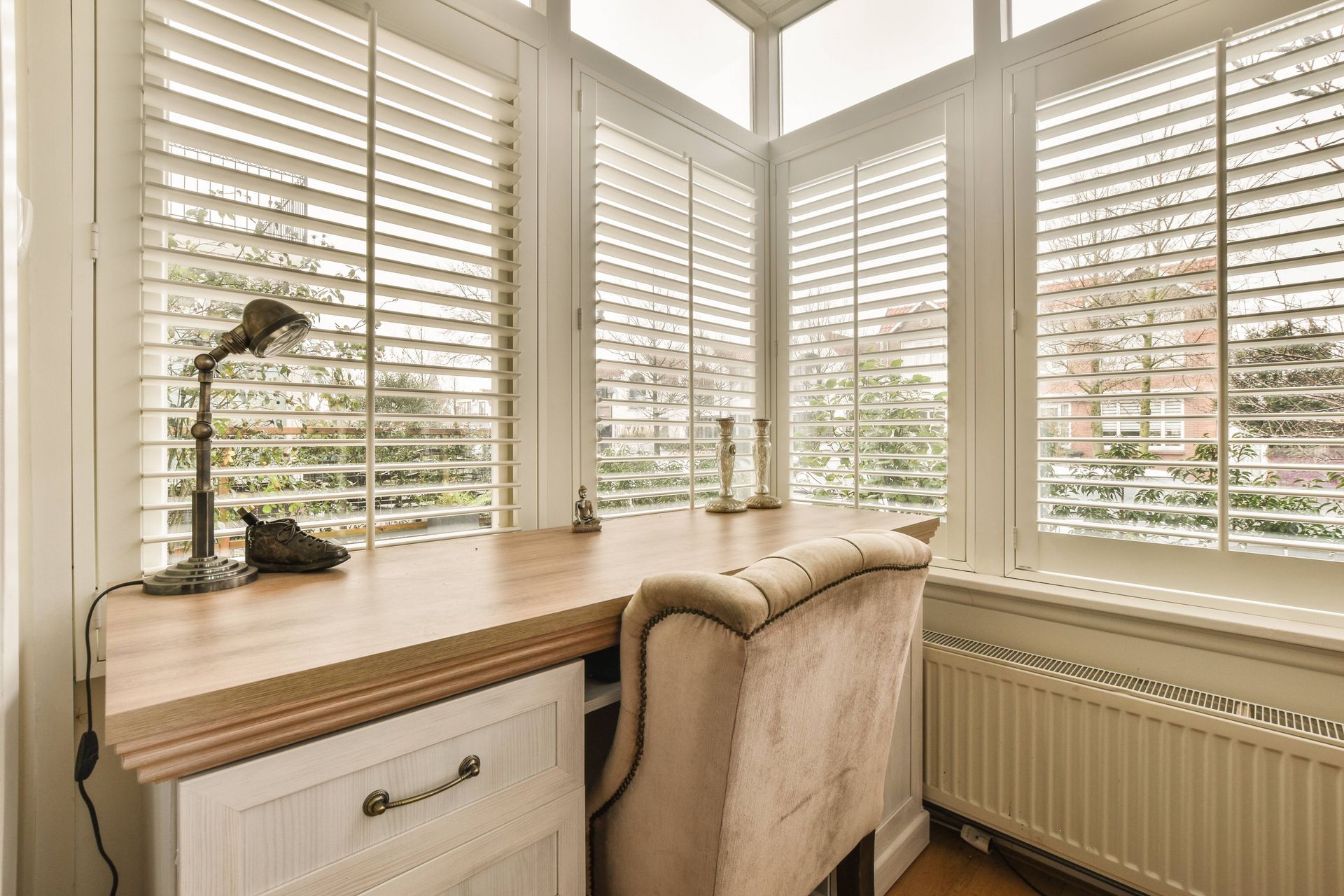 Home office with a traditional interior and white interior shutters adorning several windows around the room near Houston, TX