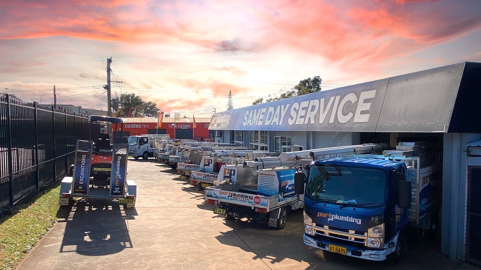 A Line of Blue Work Trucks Parked Outside a Facility — Port Macquarie Plumbing In Port Macquarie, NSW