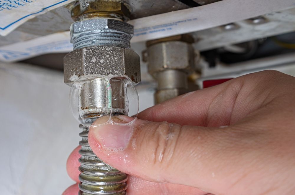 A Hand Touching a Leaking Gas Line — Port Macquarie Plumbing In Lake Cathie, NSW