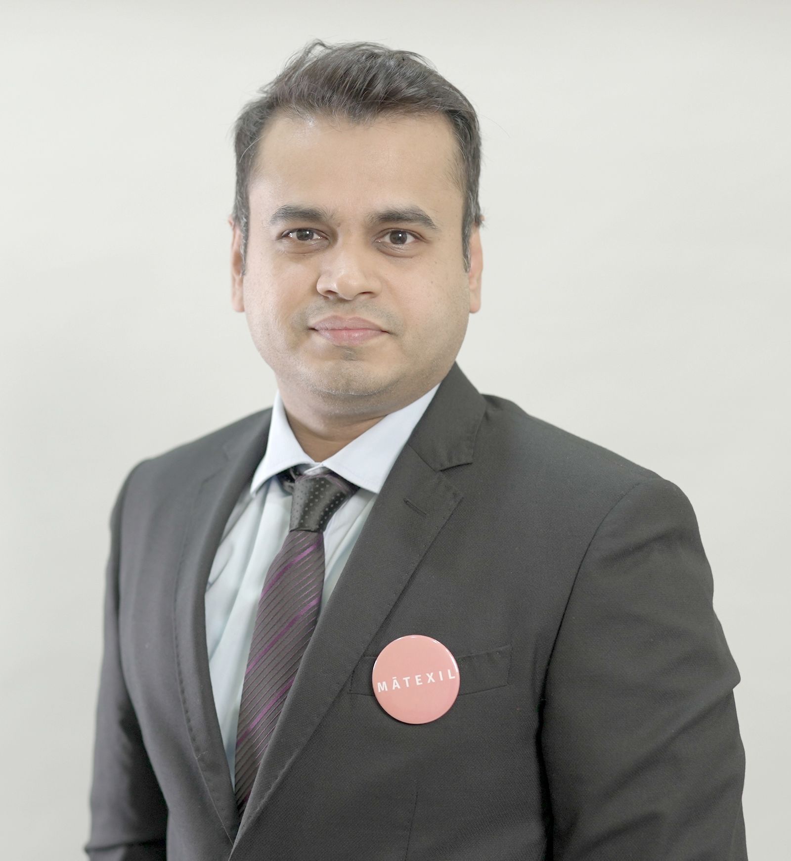 A man in a suit and tie has a button on his pocket that says matrix