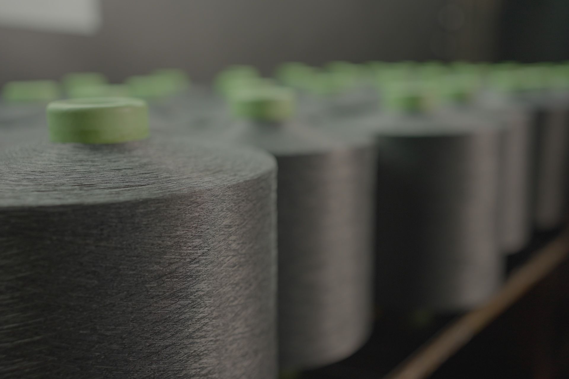 A row of spools of yarn sitting on top of a wooden shelf.