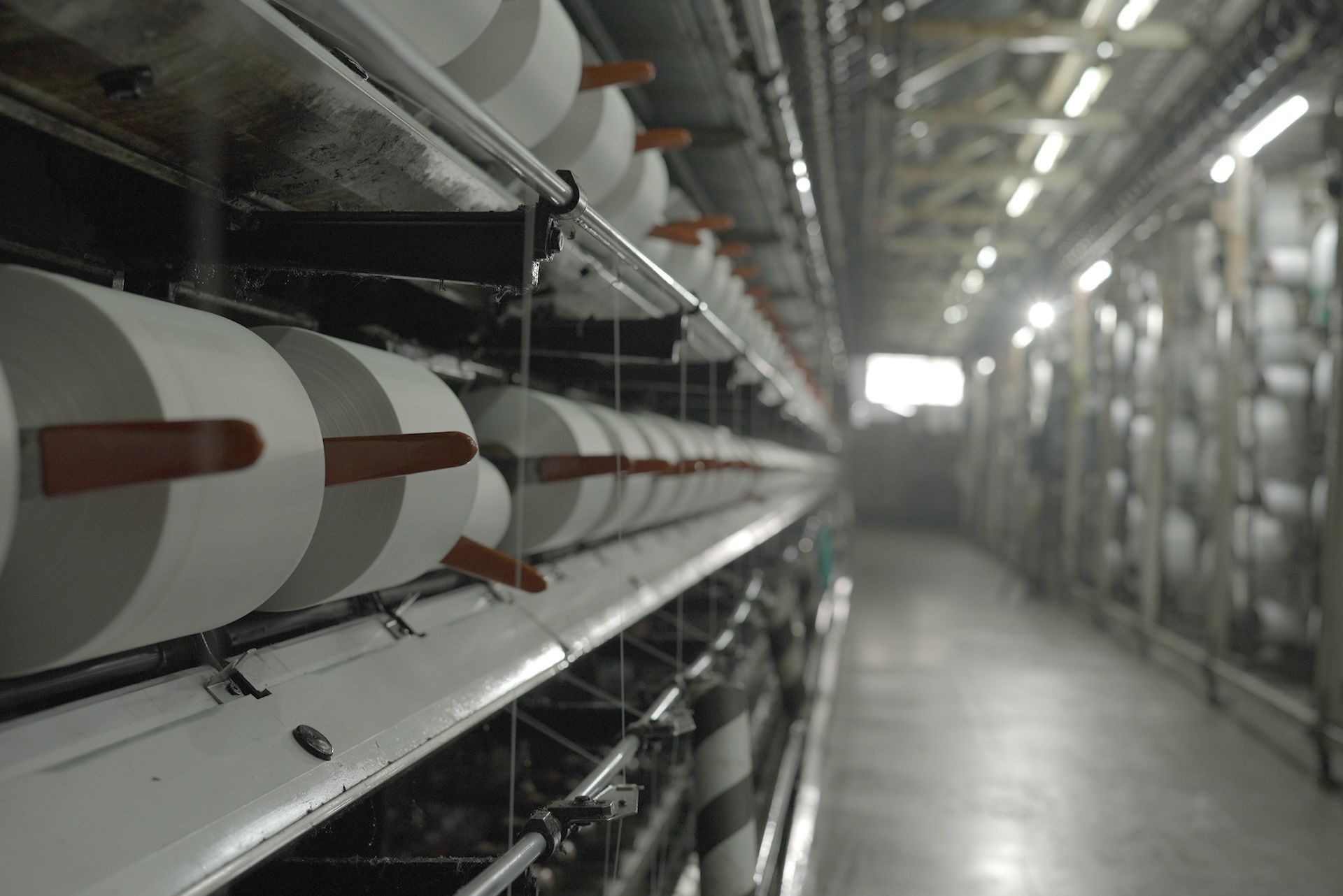 A factory with a lot of rolls of yarn hanging from the ceiling.