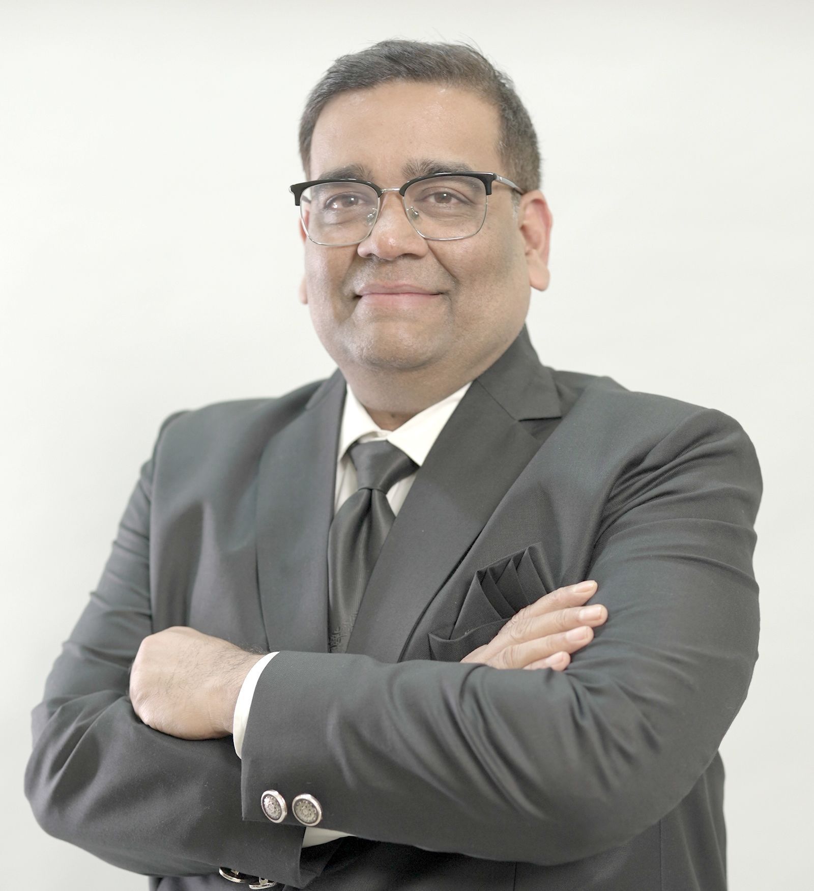 A man in a suit and tie is standing with his arms crossed.