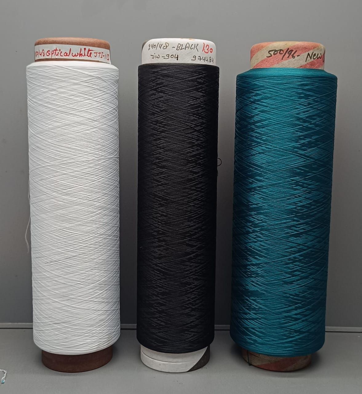 Three rolls of yarn
 are sitting next to each other on a table.