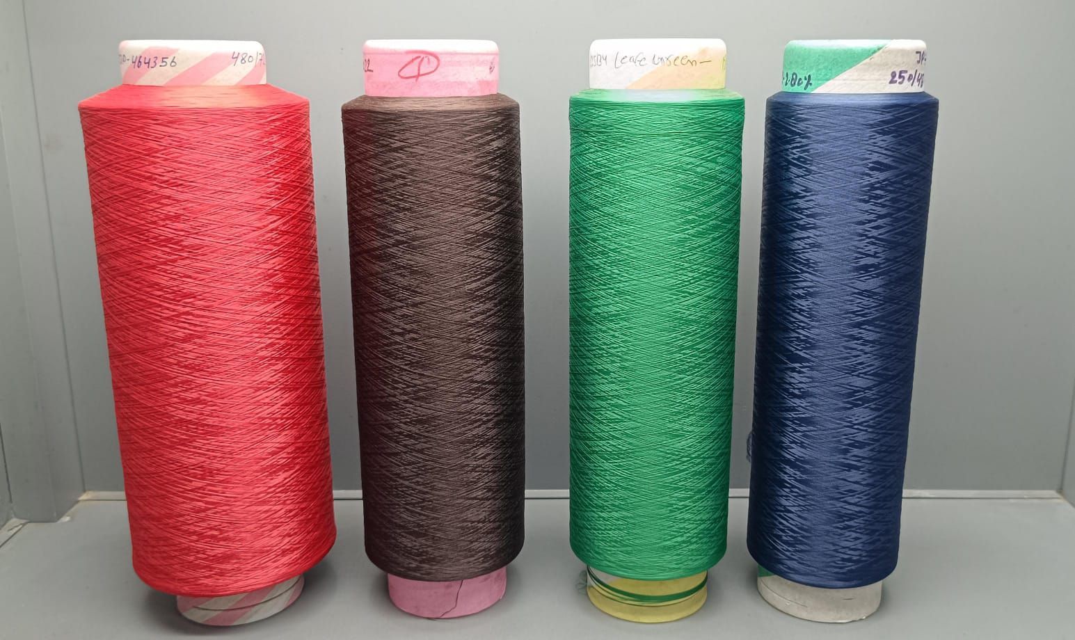 A bunch of spools of thread of different colors on a white background.