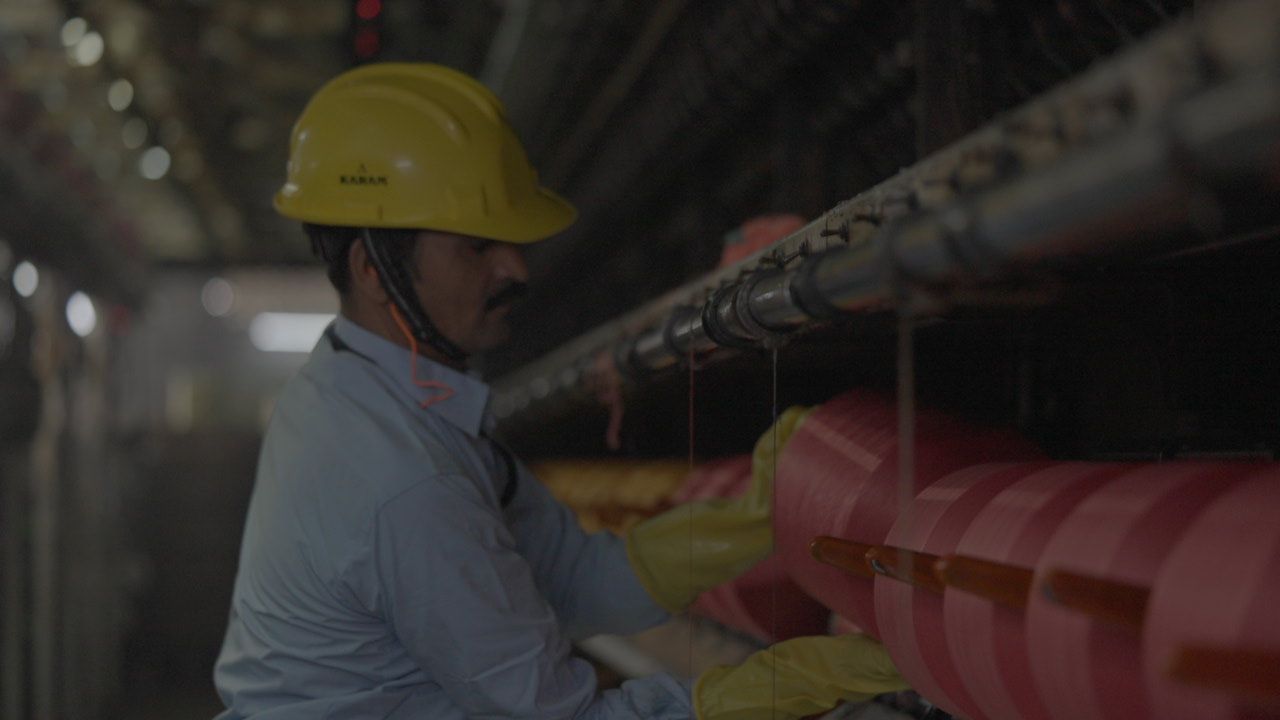 A man wearing a hard hat and gloves is working on a pipe.