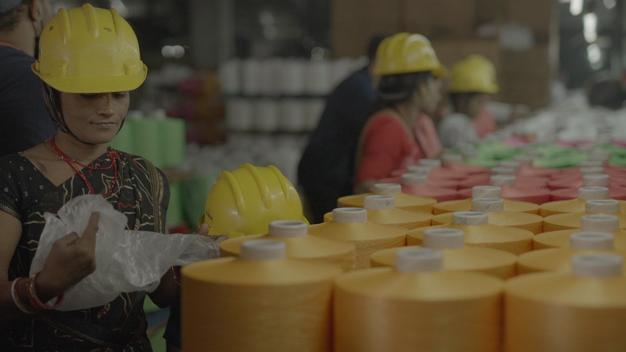 A group of people wearing hard hats are working in a factory.