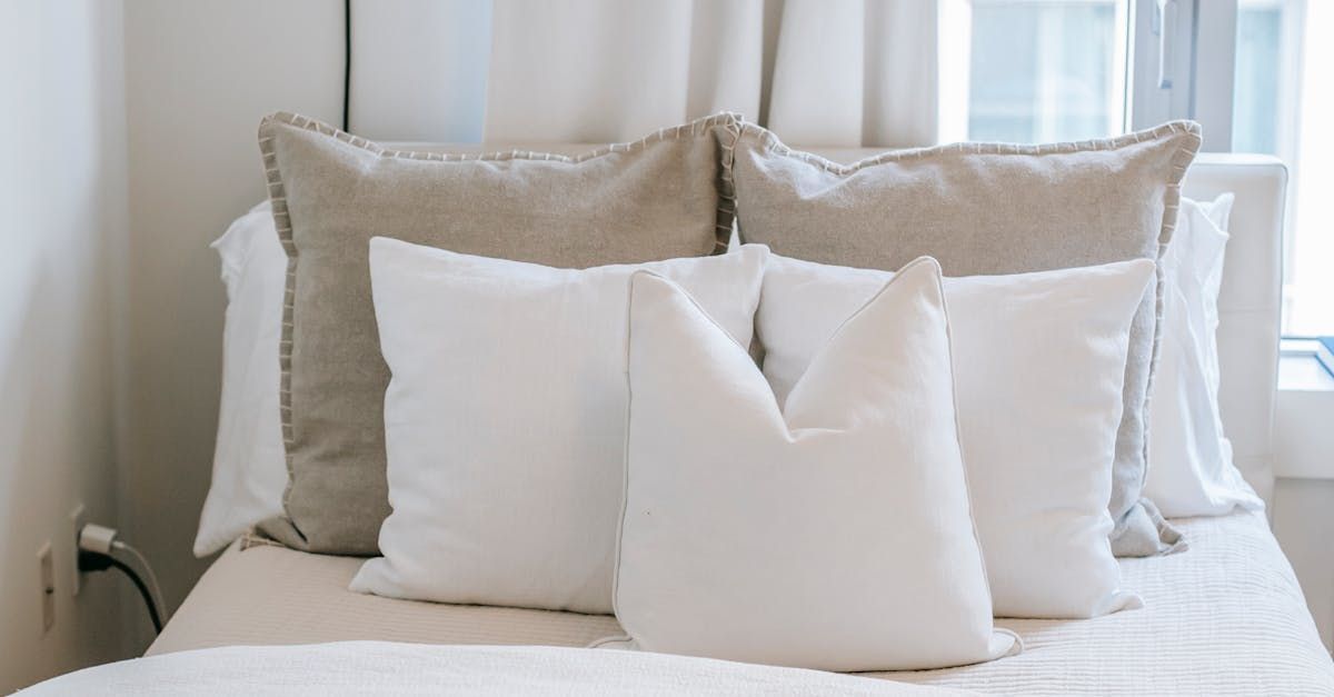 A bed with a lot of pillows on it and a window in the background.