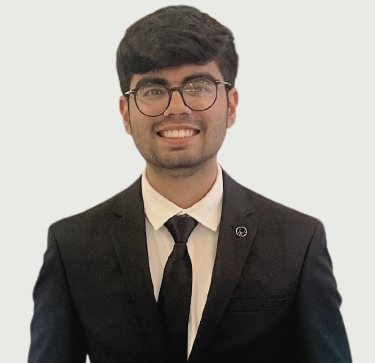 A young man wearing a suit and tie is smiling for the camera.