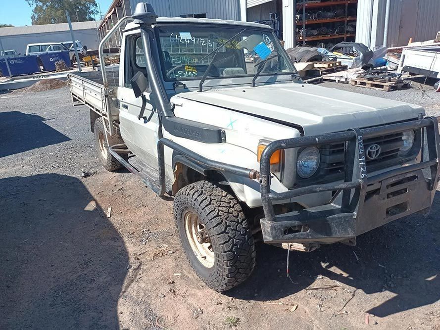 A White Truck is Parked in a Dirt Lot in Front of a Building — South West 4WD Wreckers in Harristown, QLD