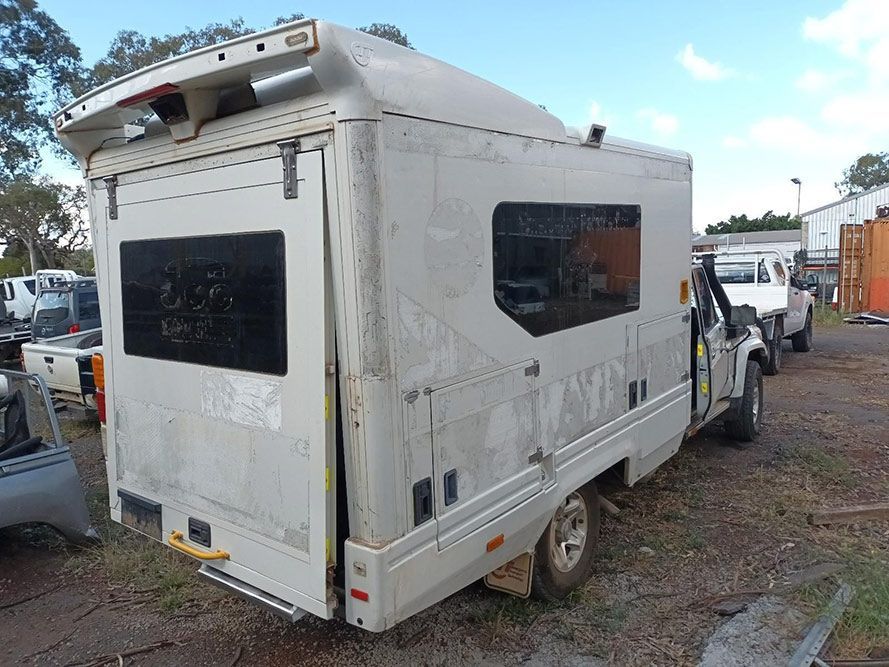 A White Camper Van is Parked in a Parking Lot — South West 4WD Wreckers In Brisbane, QLD