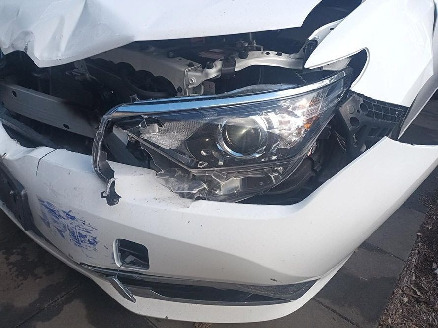 A White Car with a Broken Headlight is Parked on the Side of the Road — South West 4WD Wreckers in Harristown, QLD