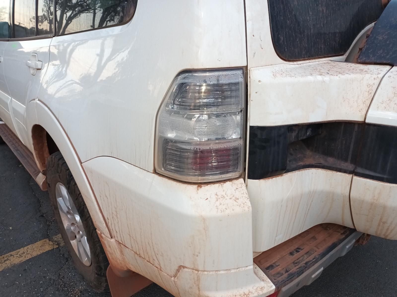 A White Suv With a Broken Tail Light is Parked on the Side of the Road — South West 4WD Wreckers In Brisbane, QLD