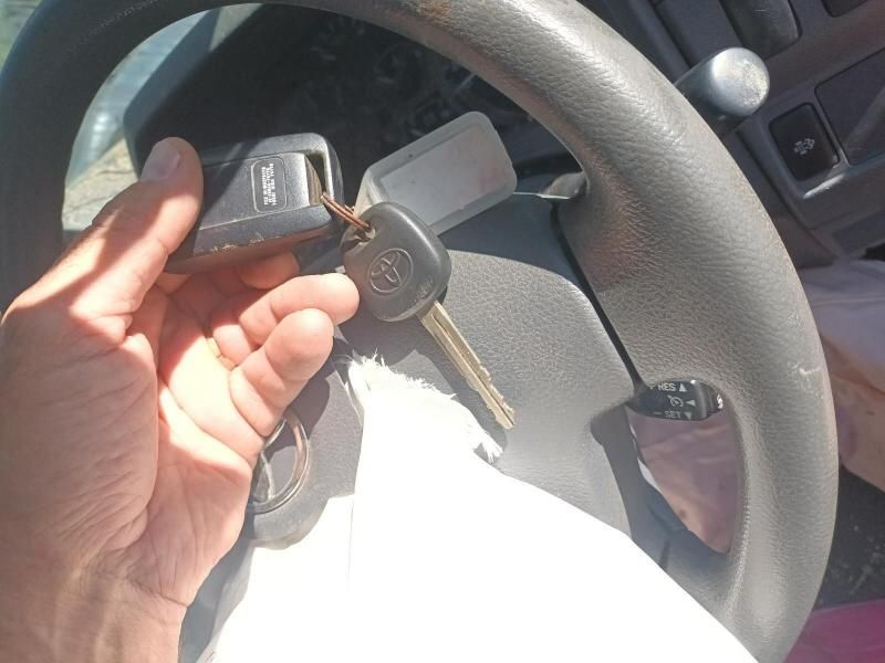 A Person is Holding a Car Key in Front of a Steering Wheel — South West 4WD Wreckers In Harristown, QLD