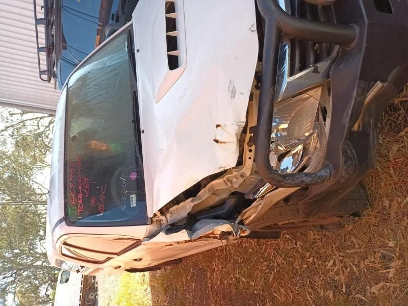A White Truck With a Broken Hood is Parked in the Grass — South West 4WD Wreckers In Harristown, QLD