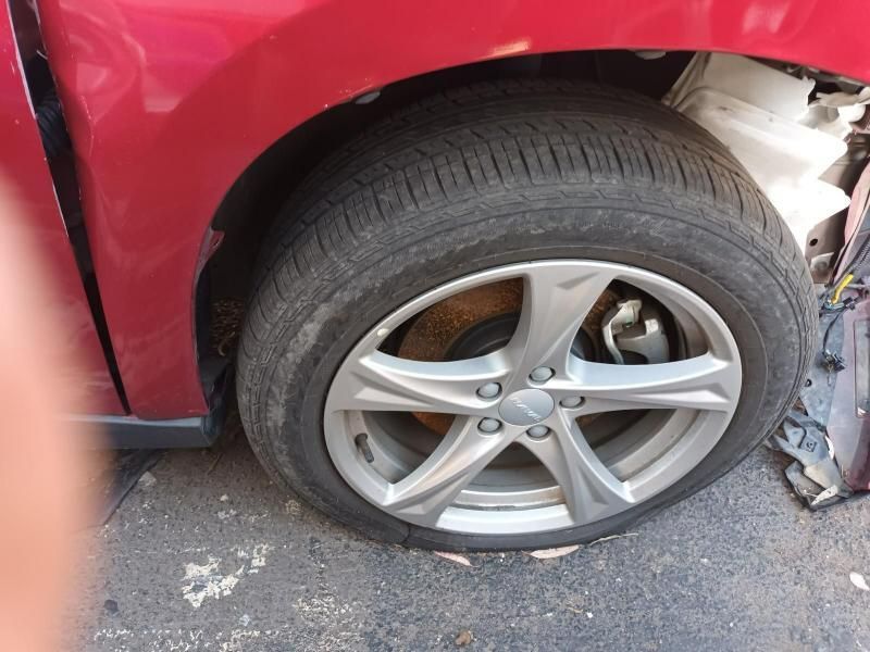 A Red Car With a Flat Tire is Sitting on the Side of the Road — South West 4WD Wreckers In Brisbane, QLD