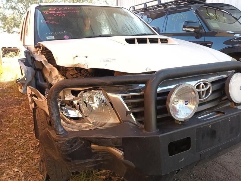 A White Toyota Truck With a Damaged Front Bumper is Parked in a Field — South West 4WD Wreckers In Harristown, QLD