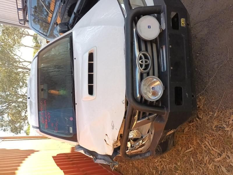 A White Toyota Truck is Parked Next to a Red Fence — South West 4WD Wreckers In Harristown, QLD