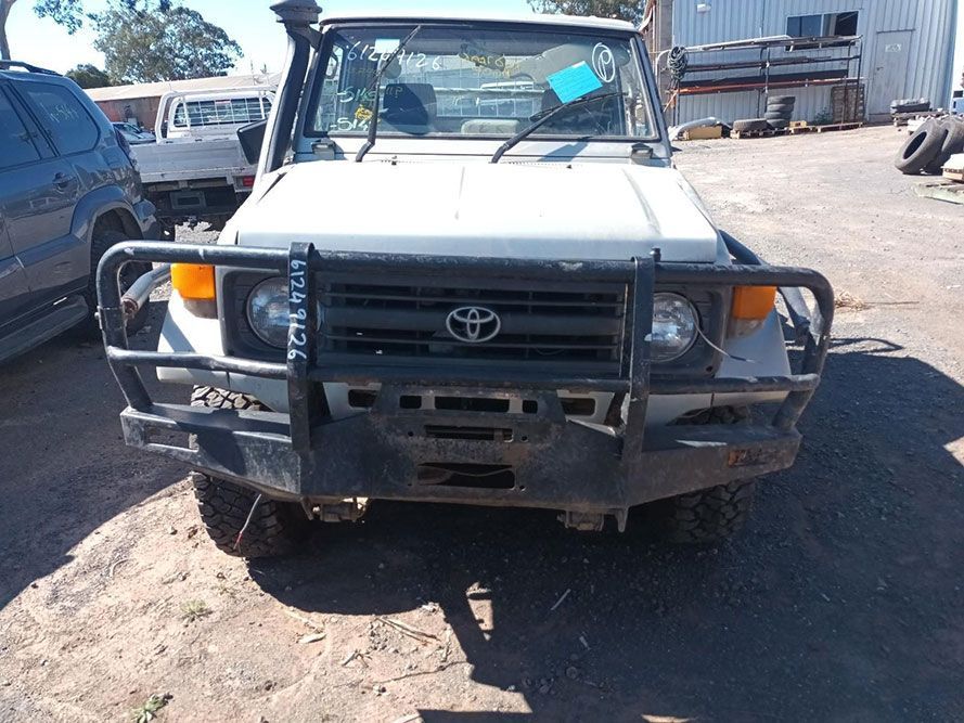 a White Toyota Truck with a Black Bumper is Parked in a Dirt Lot — South West 4WD Wreckers in Harristown, QLD