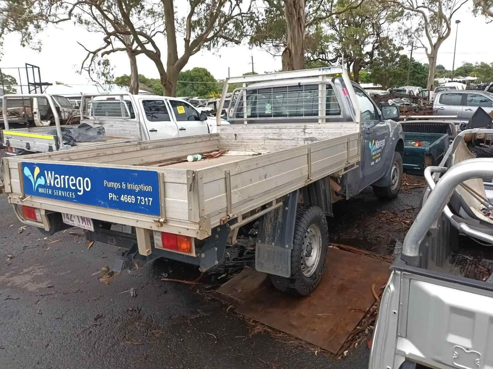 A White Truck with a Blue Sign on the Back is Parked in a Lot — South West 4WD Wreckers in Harristown, QLD 