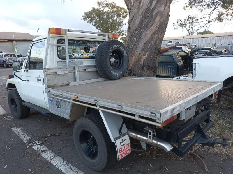 A White Truck With a Flat Bed is Parked Next to a Tree — South West 4WD Wreckers In Brisbane, QLD