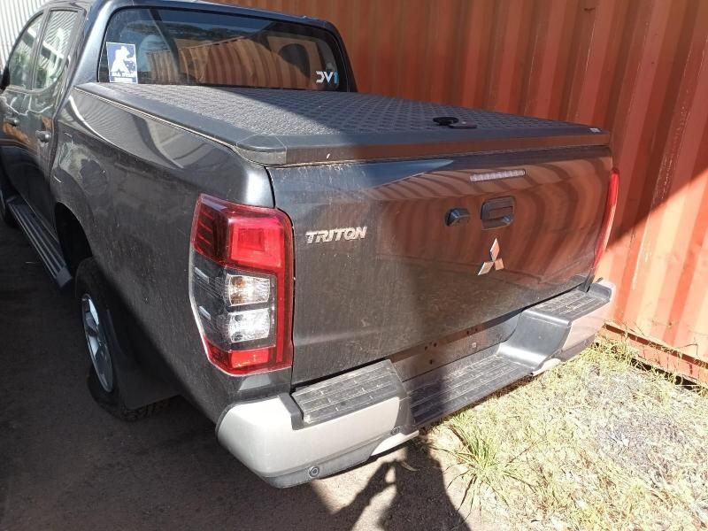 A Gray Mitsubishi Triton Truck is Parked in Front of a Red Container — South West 4WD Wreckers In Harristown, QLD