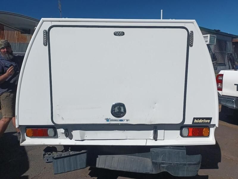 A Man is Standing Next to a White Truck With a Canopy on It — South West 4WD Wreckers In Harristown, QLD