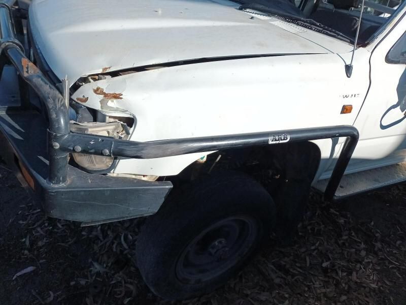 A White Truck With a Broken Hood is Parked in the Dirt — South West 4WD Wreckers In Brisbane, QLD